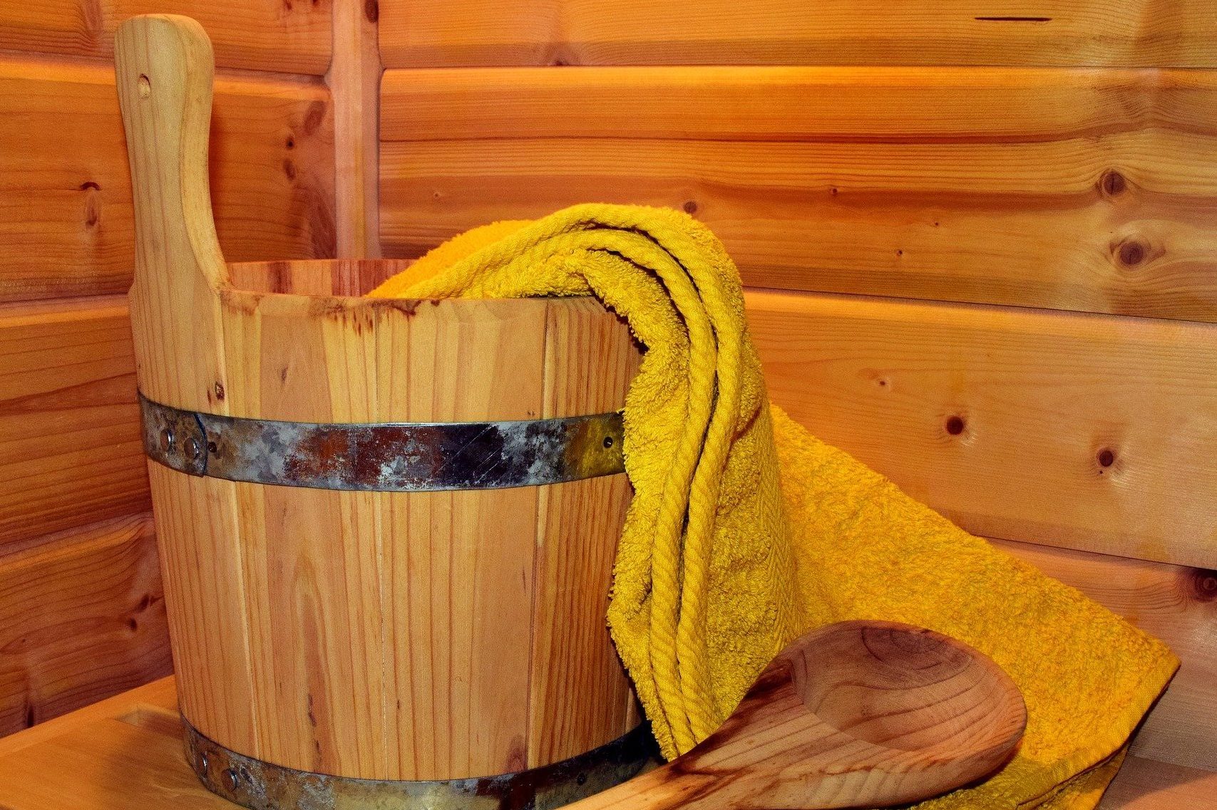 Sauna - sivun kuva jossa on löylykiulu ja -kauha sekä pyyhe. 